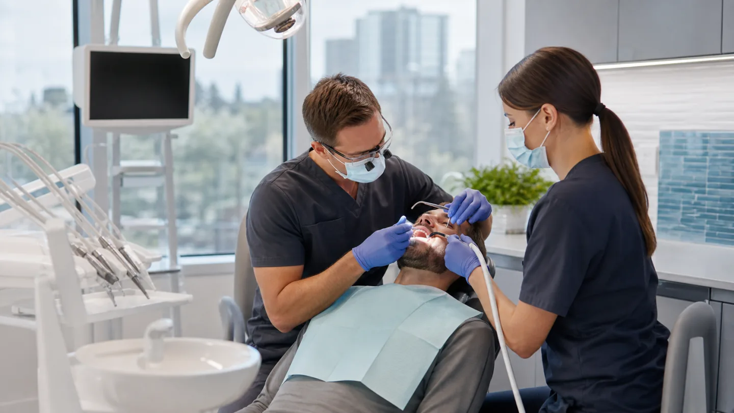 A dentist and assistant carefully restoring a tooth with a dental filling